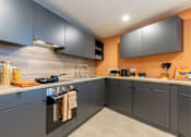 Thumbnail 13 of 35 - A kitchen with grey cabinets and a black oven.