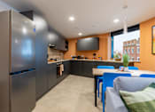 Thumbnail 14 of 35 - A modern kitchen with a refrigerator, stove, and dining table.