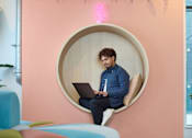 Thumbnail 30 of 35 - A man is sitting on a circular chair with a laptop.