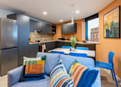 Thumbnail 22 of 35 - A modern kitchen with a blue couch and striped pillows.