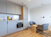 Thumbnail 27 of 35 - A modern kitchen with a wooden floor and white walls.