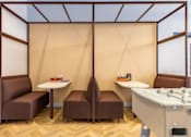 Thumbnail 17 of 41 - A room with brown chairs and a white table with a glass partition.