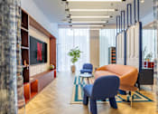 Thumbnail 13 of 41 - A modern living room with a blue chair and a TV on the wall.