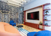 Thumbnail 28 of 41 - A living room with a large screen and a blue chair.