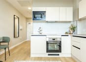 Thumbnail 64 of 65 - A modern kitchen with white cabinets and a black oven.