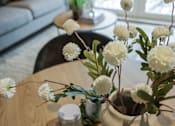 Thumbnail 34 of 38 - A vase with white flowers sits on a wooden table.