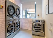 Thumbnail 41 of 41 - A row of industrial sized washing machines in a laundry room.