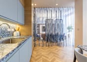 Thumbnail 21 of 41 - A kitchen with a marble countertop and wooden flooring.