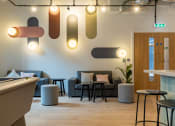 Thumbnail 13 of 35 - a lobby with couches and stools and a bar and lights on the ceiling