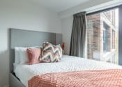Thumbnail 13 of 15 - a bedroom with a large window and a bed with pillows