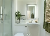 Thumbnail 10 of 17 - A white toilet sits next to a white sink in a bathroom.