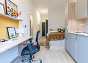 Thumbnail 11 of 17 - A room with a desk, chair, and bed.