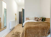 Thumbnail 8 of 17 - A bedroom with a brown bedspread and a brown rug.