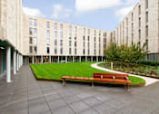 Thumbnail 49 of 51 - A long bench sits in the middle of a courtyard.
