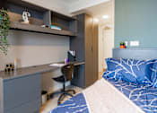 Thumbnail 32 of 51 - A bedroom with a bed, desk, and chair.