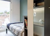 Thumbnail 46 of 51 - A bedroom with a bed and a small fridge.