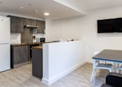 Thumbnail 38 of 51 - A modern kitchen with a white refrigerator, a microwave, and a dining table with chairs.