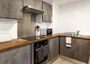 Thumbnail 36 of 51 - A modern kitchen with a stove top oven and microwave.