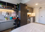 Thumbnail 41 of 51 - A bedroom with a bed, desk, and chair.