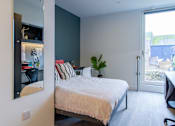 Thumbnail 39 of 51 - A bedroom with a bed, desk, and chair.