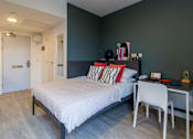 Thumbnail 40 of 51 - A bedroom with a bed, desk, and chair.
