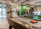 Thumbnail 15 of 51 - A pool table is in the middle of a room with a green wall and a bookshelf.