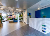 Thumbnail 1 of 51 - A modern office space with a blue tiled wall and a variety of seating options.