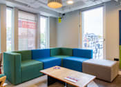 Thumbnail 9 of 51 - A blue and green sectional sofa in a room with a table and a chair.