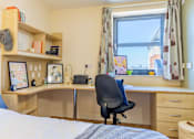 Thumbnail 25 of 35 - A bedroom with a desk and a chair.