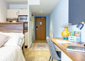 Thumbnail 16 of 21 - A bedroom with a bed, desk, and chair.