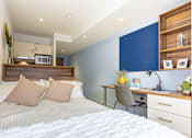 Thumbnail 4 of 41 - A bedroom with a bed, desk, and chair.