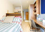 Thumbnail 7 of 41 - A bedroom with a bed, desk, and chair.