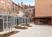 Thumbnail 36 of 36 - A courtyard with a brick building and a metal fence.