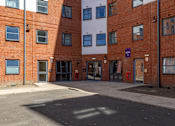 Thumbnail 17 of 35 - A red brick building with a white building in the background.