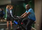 Thumbnail 48 of 85 - A man is working out on a stationary bike in a gym.