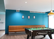 Thumbnail 2 of 21 - A pool table with a bench in front of a blue wall.