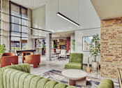 Thumbnail 3 of 17 - A modern living room with a green sofa and a brick wall.