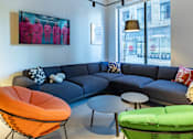 Thumbnail 2 of 29 - A living room with a grey couch, orange chair, and green chair.
