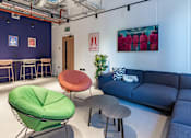 Thumbnail 3 of 29 - A room with a blue couch, a green chair, and a red chair.