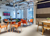 Thumbnail 4 of 29 - A modern office space with orange chairs and a wooden table.