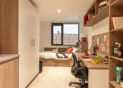 Thumbnail 24 of 29 - a small room with a desk and a bed
