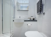 Thumbnail 19 of 19 - A white toilet in a modern bathroom with a glass shower door.