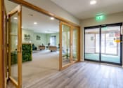 Thumbnail 3 of 19 - A room with wooden floors and glass doors leading to a balcony.