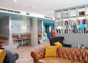 Thumbnail 21 of 21 - A room with a brown leather couch and a bookshelf filled with books.