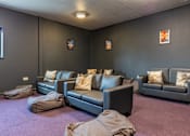 Thumbnail 29 of 30 - A living room with grey couches and pillows.