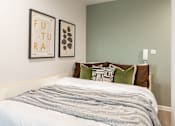 Thumbnail 32 of 49 - A bedroom with a bed, pillows, and two framed pictures on the wall.