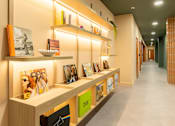 Thumbnail 16 of 49 - A hallway with a long row of shelves with books and pictures on them.