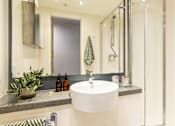 Thumbnail 38 of 49 - A bathroom with a white sink and a mirror above it.