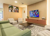 Thumbnail 2 of 49 - A living room with a green sofa, a coffee table, and a television on the wall.