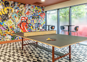 Thumbnail 9 of 49 - A ping pong table is in the middle of a room with a black and white checkered floor.